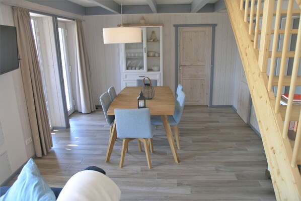 A dining area with a wooden table and chairs, a cabinet with dishes, and a staircase.