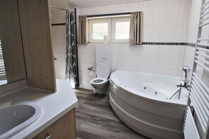 A modern bathroom with a bathtub, toilet, and shower area.