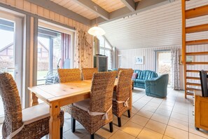 Relax in this inviting room with a dining table, comfortable sofa, and wooden bookshelf.