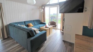 Un salon moderne avec un canapé bleu, une table basse en bois et un téléviseur à écran plat fixé au mur.