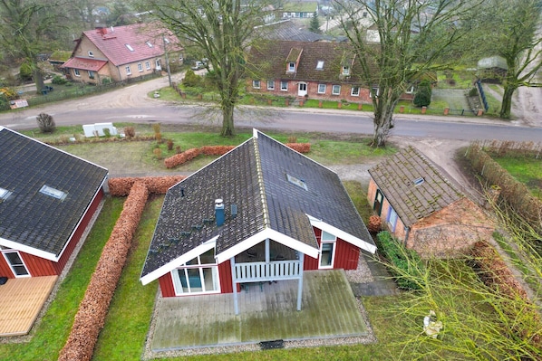 A residential area with three houses, each with a sloped roof and a small porch. The houses are surrounded by lawns and trees. - skandinavisches Ferienhaus in Mirow (Granzow)