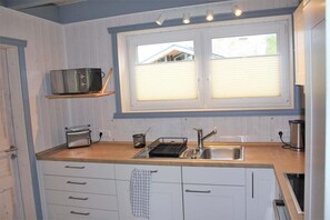 A compact kitchen with a window, a toaster, a kettle, and a sink. - skandinavisches Ferienhaus in Mirow (Granzow)