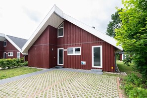 Un edificio rosso con tetto spiovente, una porta e finestre.