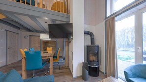 A modern interior with a dining area, sofas, a fireplace, and large windows. - exklusives skandinavisches Ferienhaus (Granzow)