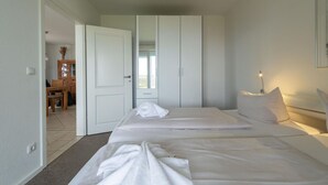 A bedroom with two beds, a wardrobe, and a bedside lamp. - liebevoll eingerichtetes Appartement (Rechlin)