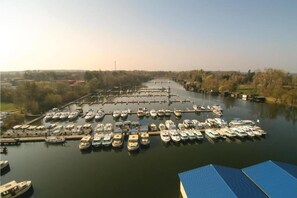A marina with numerous boats docked in a calm water body, surrounded by trees and open land. - liebevoll eingerichtetes Appartement (Rechlin)