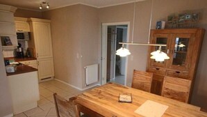 A kitchen with a wooden dining table, cabinets, and a hanging light fixture. - liebevoll eingerichtetes Appartement (Rechlin)