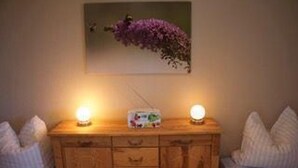 Een houten dressoir met twee bedlampen, een radio en een ingelijste foto aan de muur.