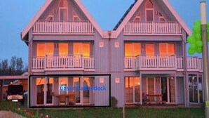 Een gebouw met twee verdiepingen, een symmetrische voorgevel, veel ramen en een balkon op elke verdieping.