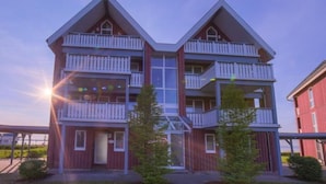 A multi-story building with a symmetrical facade, multiple balconies, and a central glass entrance.