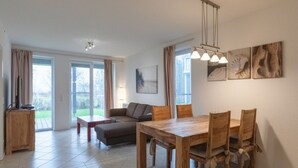 A modern living room with a wooden dining table, two sofas, and a large window with curtains. - liebevoll eingerichtetes Appartement (Rechlin)