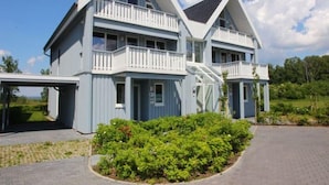 A two-story house with a balcony on the upper floor, a garage, and a well-maintained garden.
