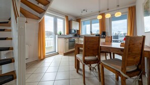 Een moderne keuken met houten kasten, een eettafel met stoelen en een trap.