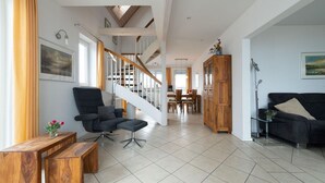 Een ruime woonkamer met een trap, houten meubels en uitzicht op de eethoek.