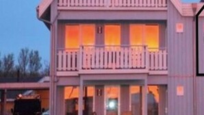 A two-story house with a balcony and a covered front porch.