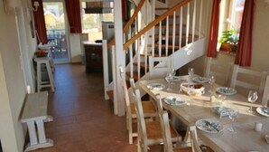 A dining area with a long table set for a meal, wooden chairs, and a staircase leading to another level.