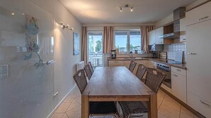 A modern kitchen with a dining area, large windows, and a view of the city. - Appartement im Ferienpark in Rechlin (Rechlin)