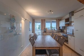 A modern kitchen with a dining area, large windows, and a view of the city. - Appartement im Ferienpark in Rechlin (Rechlin)