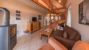 Un vaste espace de vie doté d’une cheminée, de meubles en bois et d’un escalier menant à un niveau supérieur.