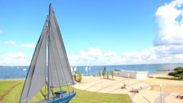 A sailboat on a calm body of water with a clear sky and a distant shoreline.