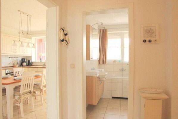 A kitchen with white cabinets, a wooden countertop, and a dining area with white chairs.