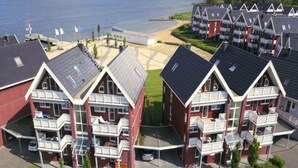 A coastal residential area with modern, multi-story buildings featuring balconies and a beach in the background.