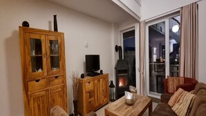 Un saló acollidor amb un armari de fusta, televisió, llar de foc i un sofà.