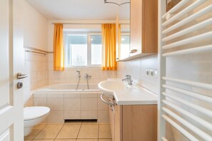 A modern bathroom with a bathtub, a sink, and a toilet.