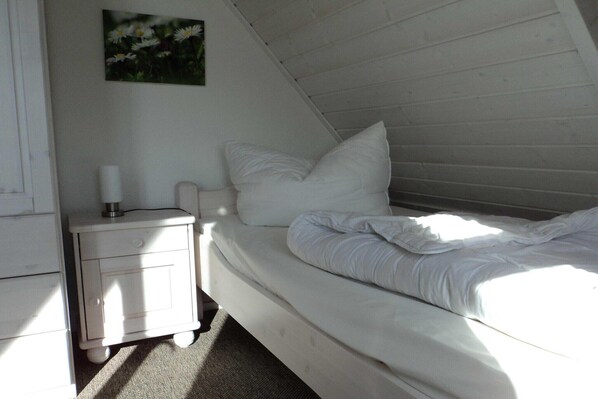 A bedroom with a single bed, a bedside table with a lamp, and a wall-mounted picture. - liebevoll eingerichtetes Appartement (Rechlin)