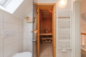 A modern bathroom with a glass shower enclosure, a wooden sauna, and a white radiator. - exklusives Appartement in Rechlin (Rechlin)