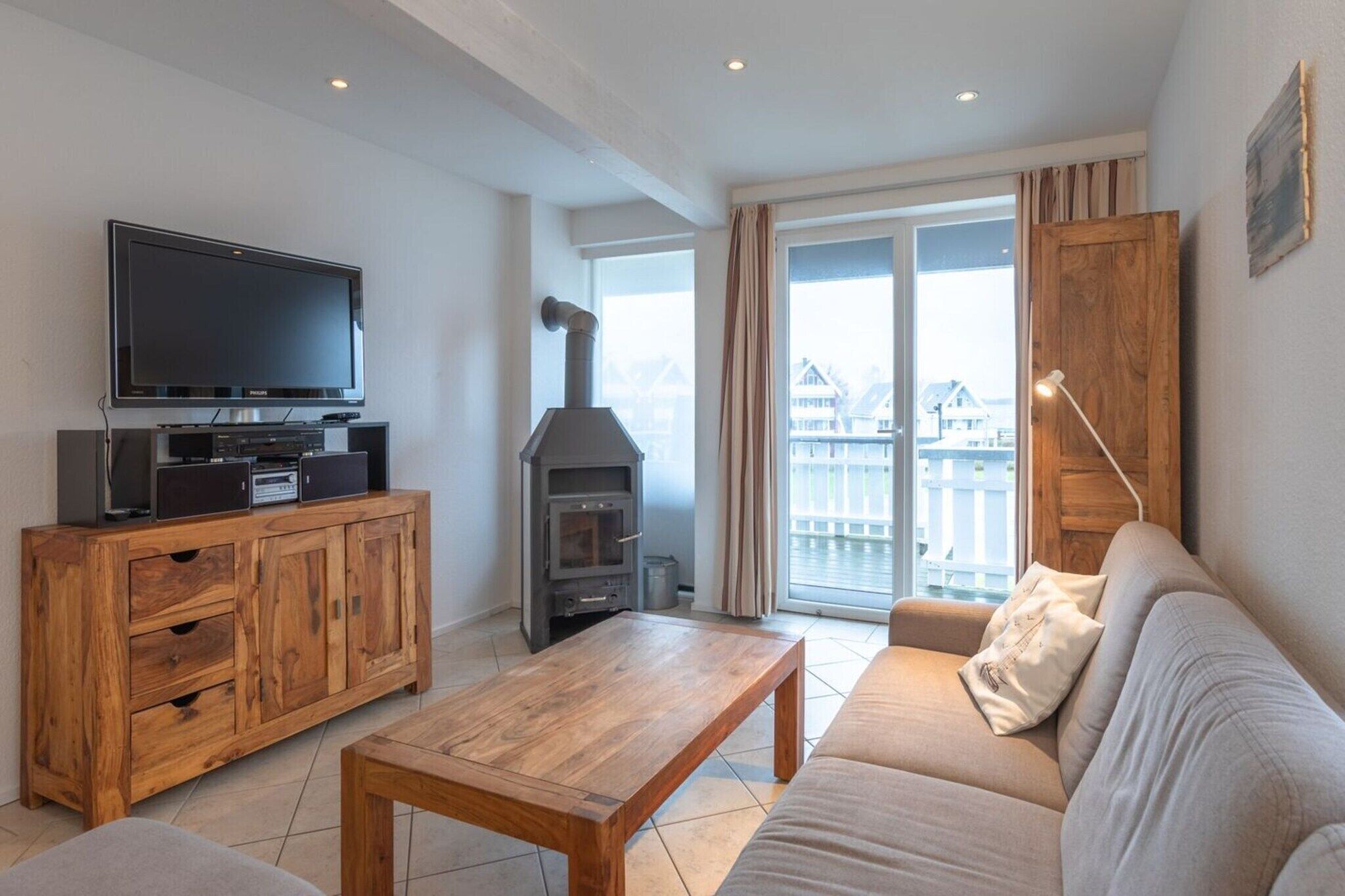 Una sala de estar con televisor, aparador de madera, chimenea, sofá y balcón con vistas.