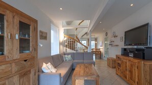 Un salon spacieux avec un meuble en bois, un canapé gris, une table basse en bois et un téléviseur.