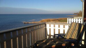 A deck with a view of the sea, featuring a chair and a white fence. - Appartement im Ferienpark in Rechlin (Rechlin)