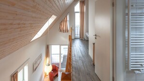 A high-ceilinged room with wooden beams, a staircase, and a view to a lower level. - Appartement im Ferienpark in Rechlin (Rechlin)