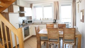 A kitchen with white cabinets, a wooden dining table, and chairs. - liebevoll eingerichtetes Appartement (Rechlin)