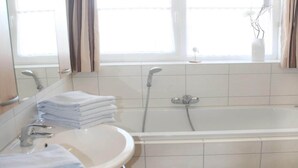 Une salle de bain avec un lavabo, un miroir et une baignoire.