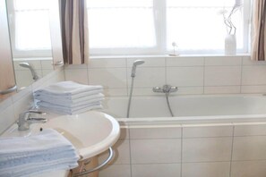 A bathroom with a sink, mirror, and bathtub.