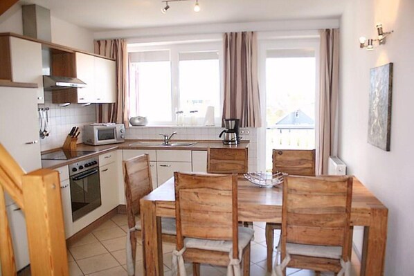 A compact kitchen with a dining area, including a stove, microwave, and sink.