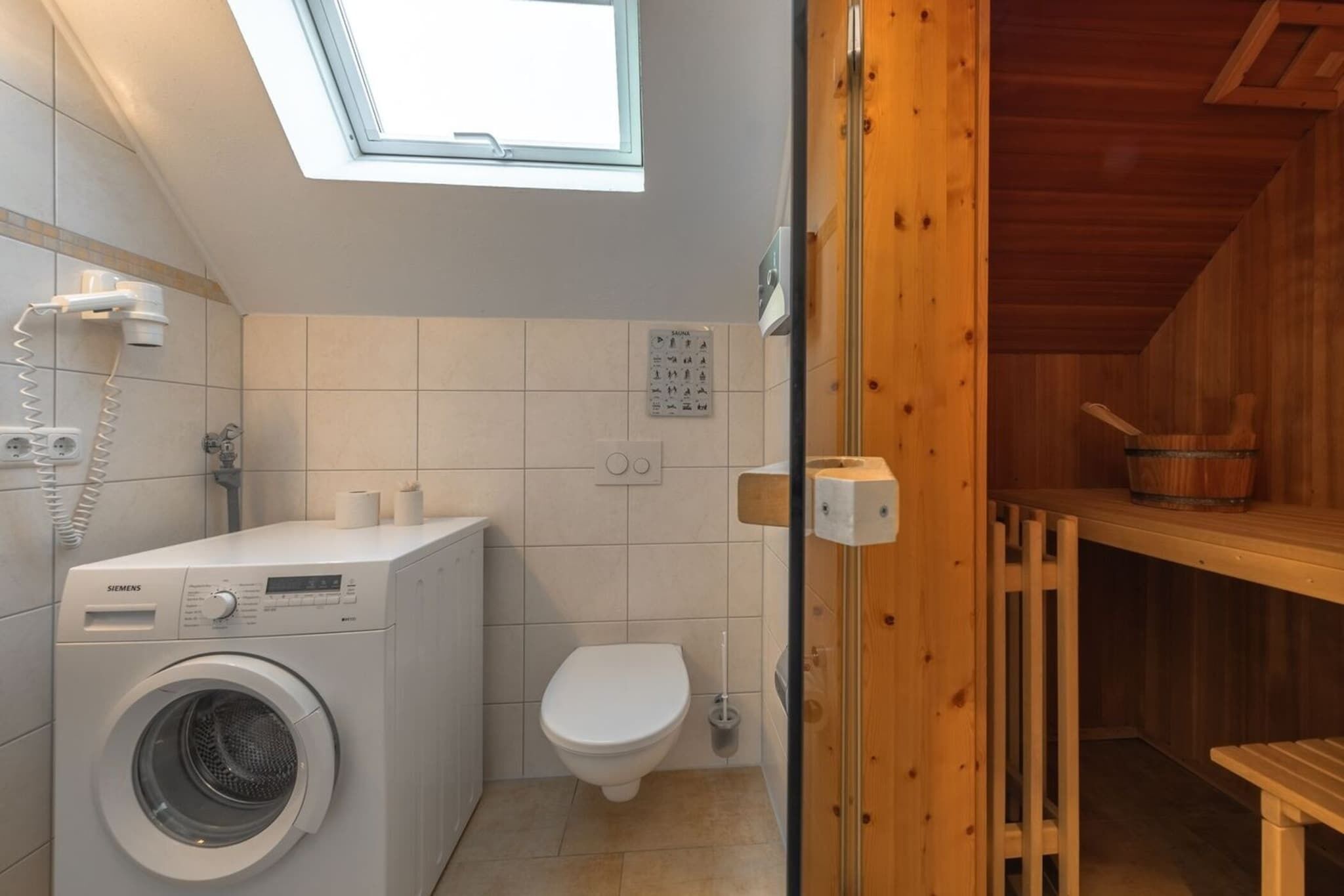 Un baño pequeño con lavadora, inodoro y panel de control de sauna.