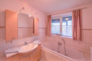A bathroom with a bathtub, a sink, and a mirror.