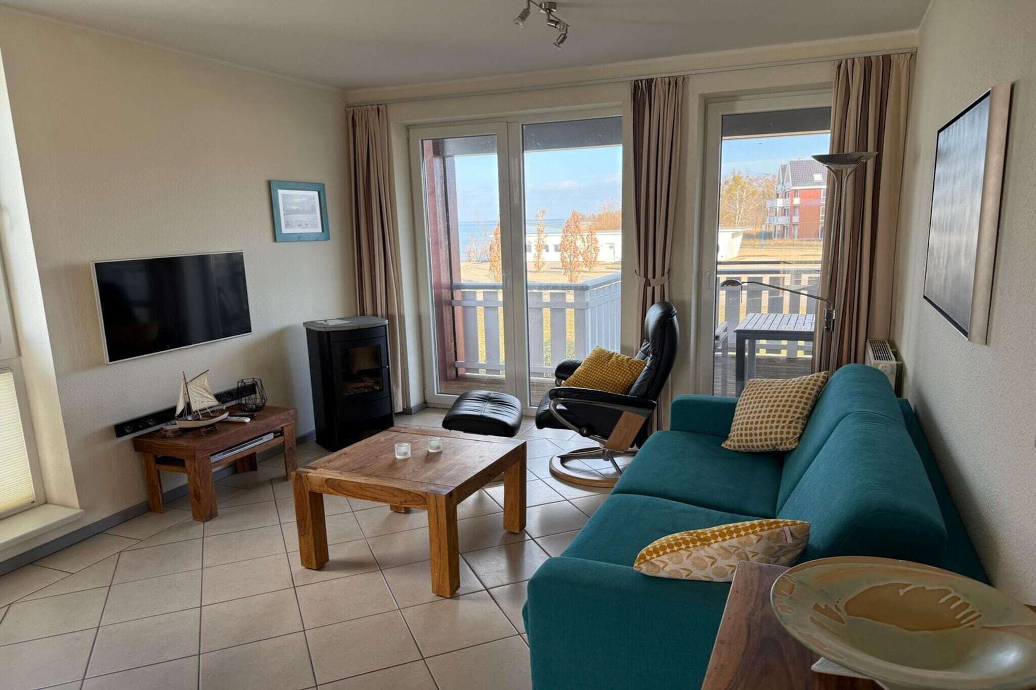 Una sala de estar con sofá, mesa de centro, televisor y balcón con vistas.