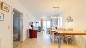 A spacious living area with a dining table, red armchair, and a kitchen in the background. - exklusives Appartement in Rechlin (Rechlin)