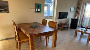 A dining area with a wooden table and chairs, a small side table with a candle, and a television on a stand. - exklusives Appartement in Rechlin (Rechlin)