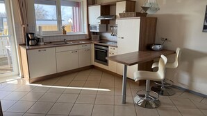 A modern kitchen with a dining area, including a table and two bar stools. - exklusives Appartement in Rechlin (Rechlin)