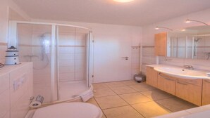 A modern bathroom with a shower, toilet, and sink. - Appartement im Ferienpark in Rechlin (Rechlin)