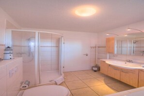 A modern bathroom with a shower, toilet, and sink. - Appartement im Ferienpark in Rechlin (Rechlin)