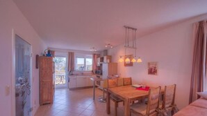 A spacious kitchen with a dining area, wooden furniture, and a view to the outside. - Appartement im Ferienpark in Rechlin (Rechlin)