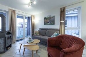 A modern living room with a grey sofa, a red armchair, a small coffee table, and a fireplace. - liebevoll eingerichtetes Appartement (Rechlin)