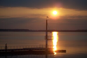 Um pôr do sol sobre águas tranquilas com um píer que se estende na água.