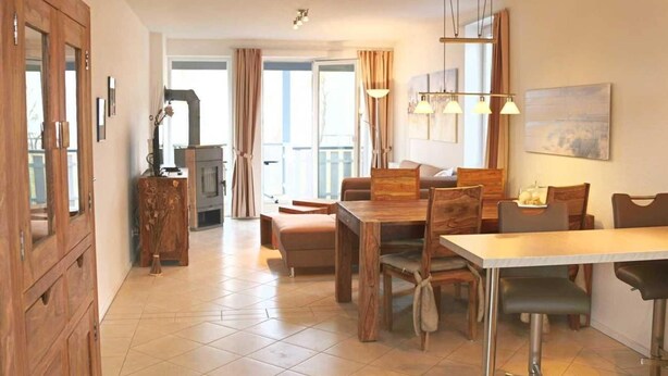 A spacious living area with a wooden dining table, comfortable seating, and a view to the outside. - liebevoll eingerichtetes Appartement (Rechlin)